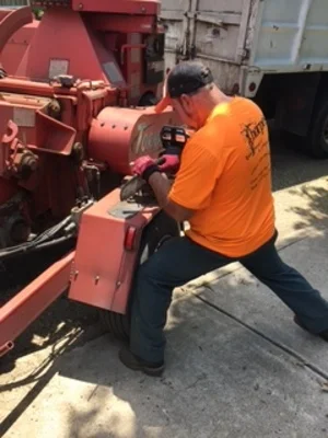 Technician servicing red wood chipper hydraulic system and connections